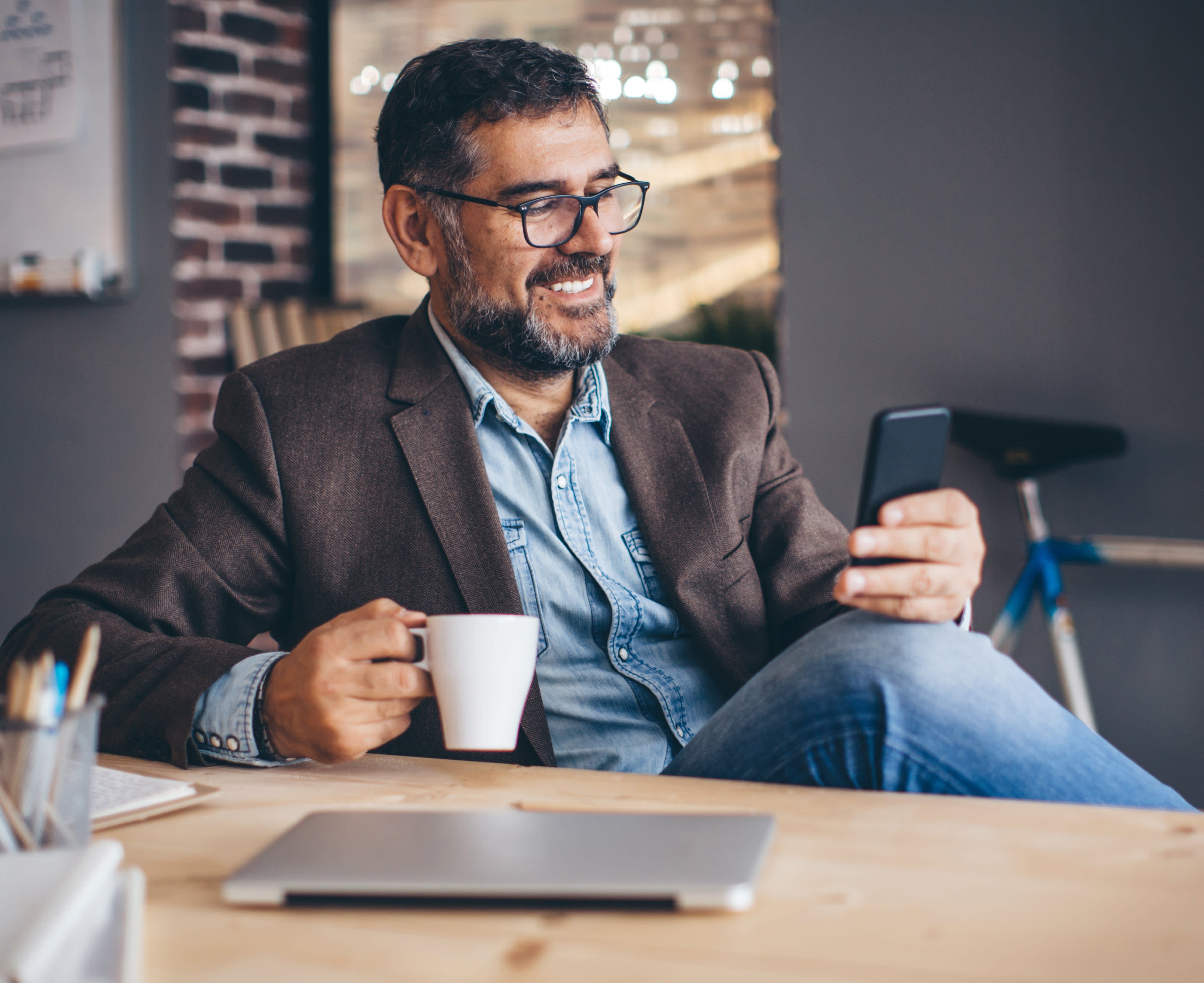 Man with cup of coffee looking at mobile phone 